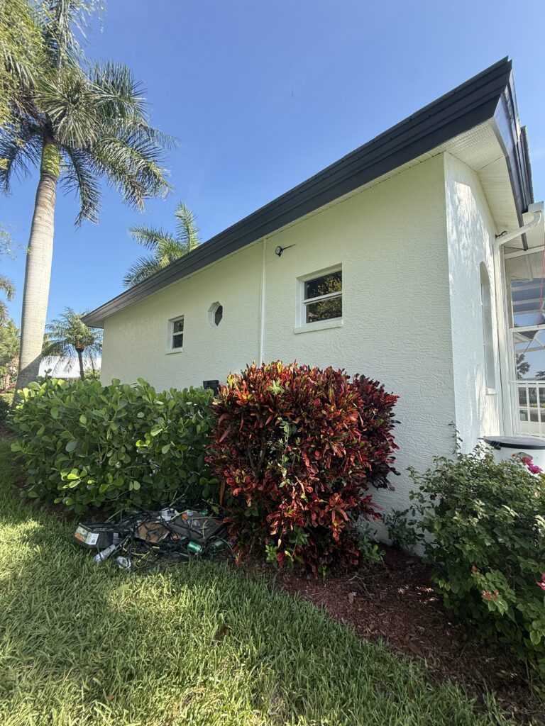 Newly painted white stucco exterior of a residential home with dark trim and lush landscaping.